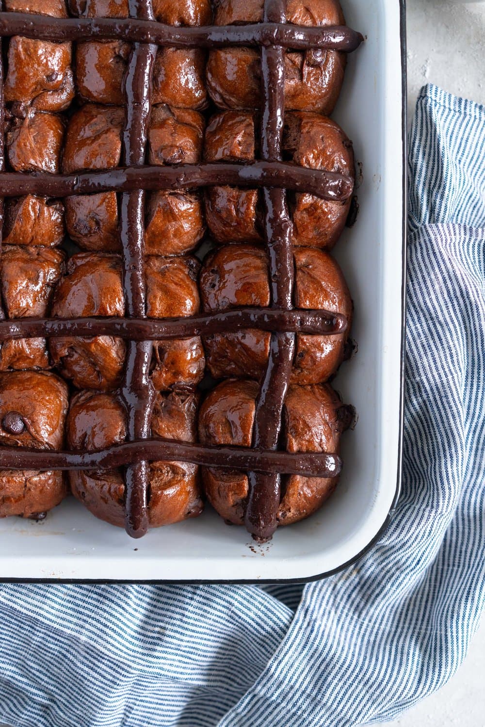 Dark Chocolate and Cardamom Hot Cross Buns with Chocolate Pastry Cream Cross. These are the perfect twist on the traditional hot cross bun - the dough is soft and smooth, and the pastry cream cross adds a beautiful fudgy finish to the bun. These are a must make this Easter! #hotcrossbuns #chocolatehotcrossbun #cardamomhotcrossbun #custardcross