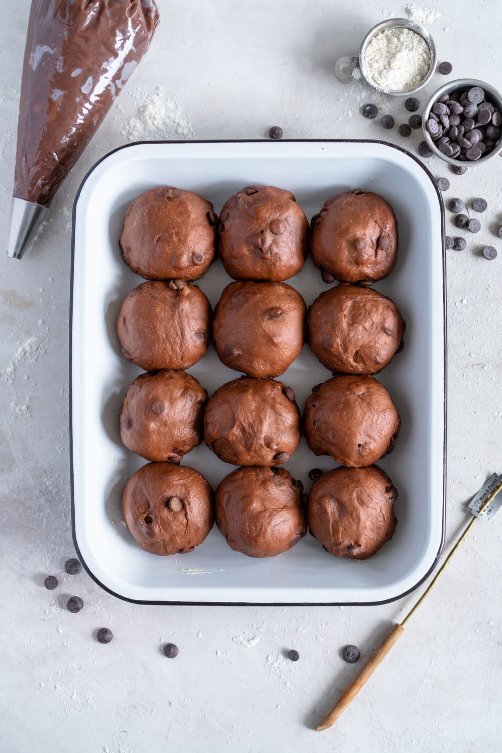 Dark Chocolate and Cardamom Hot Cross Buns with Chocolate Pastry Cream Cross. These are the perfect twist on the traditional hot cross bun - the dough is soft and smooth, and the pastry cream cross adds a beautiful fudgy finish to the bun. These are a must make this Easter! #hotcrossbuns #chocolatehotcrossbun #cardamomhotcrossbun #custardcross