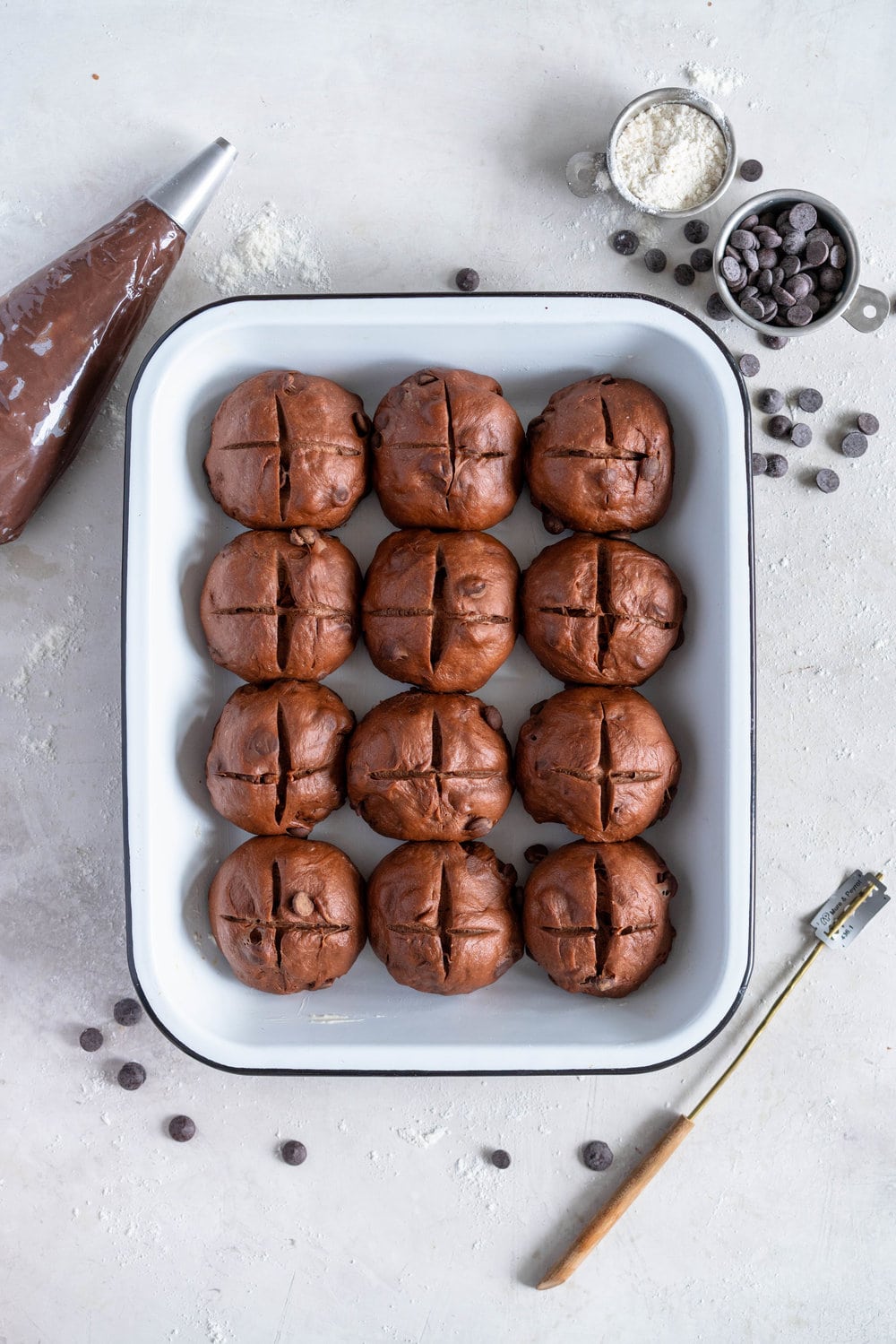Dark Chocolate and Cardamom Hot Cross Buns with Chocolate Pastry Cream Cross. These are the perfect twist on the traditional hot cross bun - the dough is soft and smooth, and the pastry cream cross adds a beautiful fudgy finish to the bun. These are a must make this Easter! #hotcrossbuns #chocolatehotcrossbun #cardamomhotcrossbun #custardcross