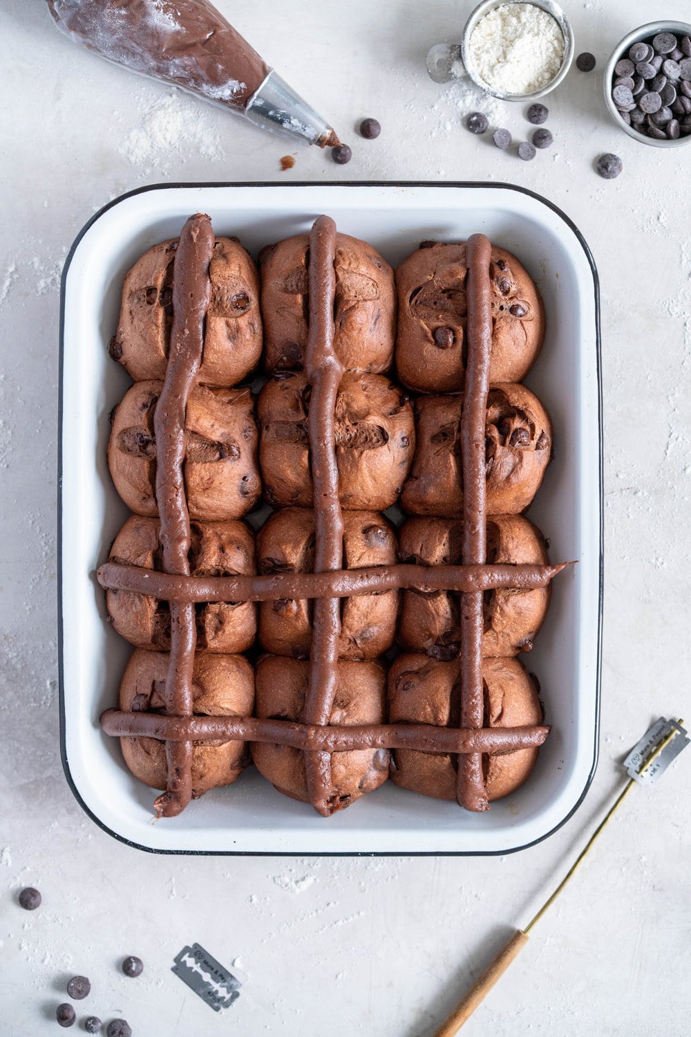 Dark Chocolate and Cardamom Hot Cross Buns with Chocolate Pastry Cream Cross. These are the perfect twist on the traditional hot cross bun - the dough is soft and smooth, and the pastry cream cross adds a beautiful fudgy finish to the bun. These are a must make this Easter! #hotcrossbuns #chocolatehotcrossbun #cardamomhotcrossbun #custardcross