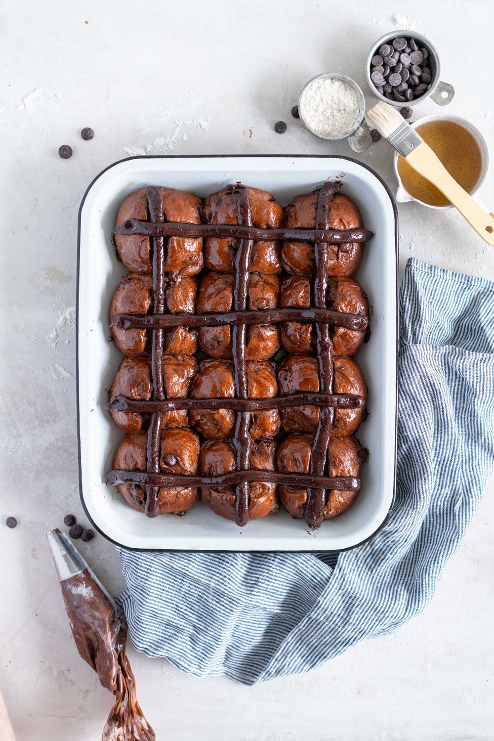 Dark Chocolate and Cardamom Hot Cross Buns with Chocolate Pastry Cream Cross. These are the perfect twist on the traditional hot cross bun - the dough is soft and smooth, and the pastry cream cross adds a beautiful fudgy finish to the bun. These are a must make this Easter! #hotcrossbuns #chocolatehotcrossbun #cardamomhotcrossbun #custardcross