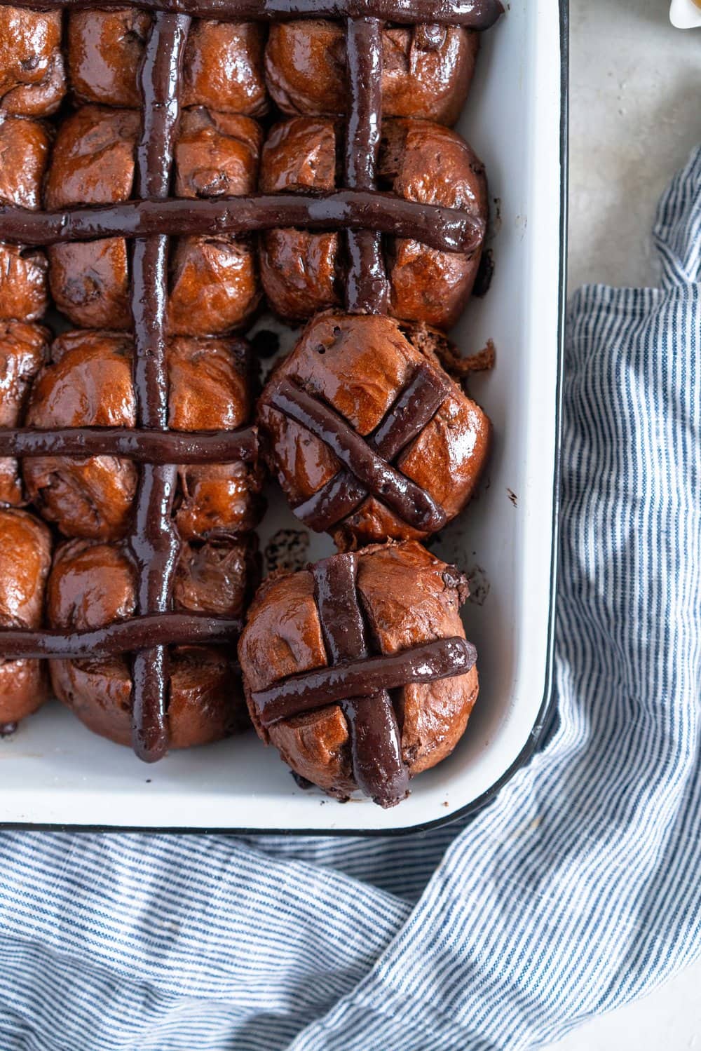 Dark Chocolate and Cardamom Hot Cross Buns with Chocolate Pastry Cream Cross. These are the perfect twist on the traditional hot cross bun - the dough is soft and smooth, and the pastry cream cross adds a beautiful fudgy finish to the bun. These are a must make this Easter! #hotcrossbuns #chocolatehotcrossbun #cardamomhotcrossbun #custardcross