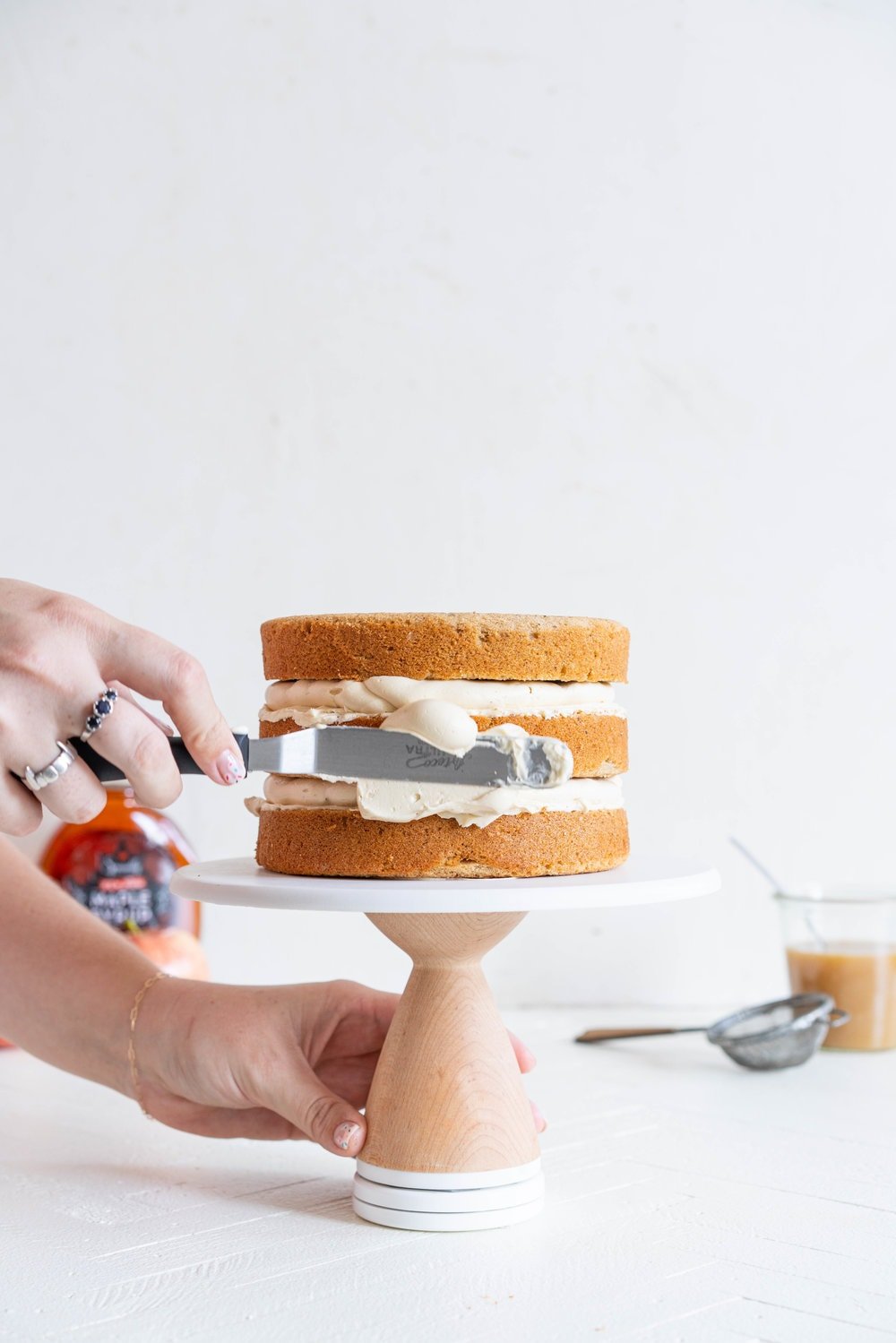 Spiced Brown Sugar cake with Cinnamon Apple Filling and Maple Caramel German Buttercream. This layer cake screams fall - a cozy brown sugar spice cake is layered with a cinnamon apple filling and a maple caramel german buttercream, then finished with a maple salted caramel drizzle and a dusting of cinnamon. This is the perfect fall inspired layer cake #autumncake #applecake #layercake