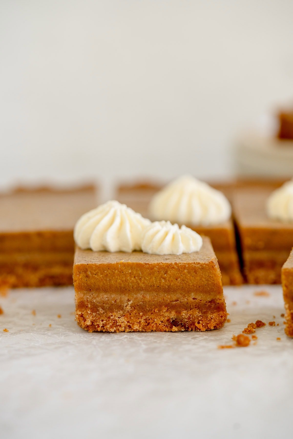 pumpkin pie bars with whipped cream on parchment paper